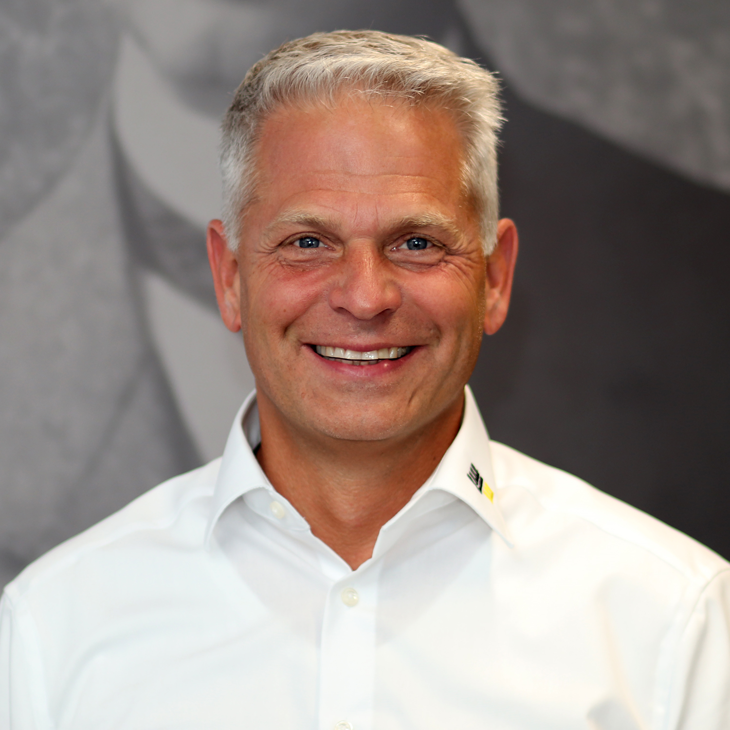 Ein Mann mit weißen Haaren trägt ein weißes Hemd.