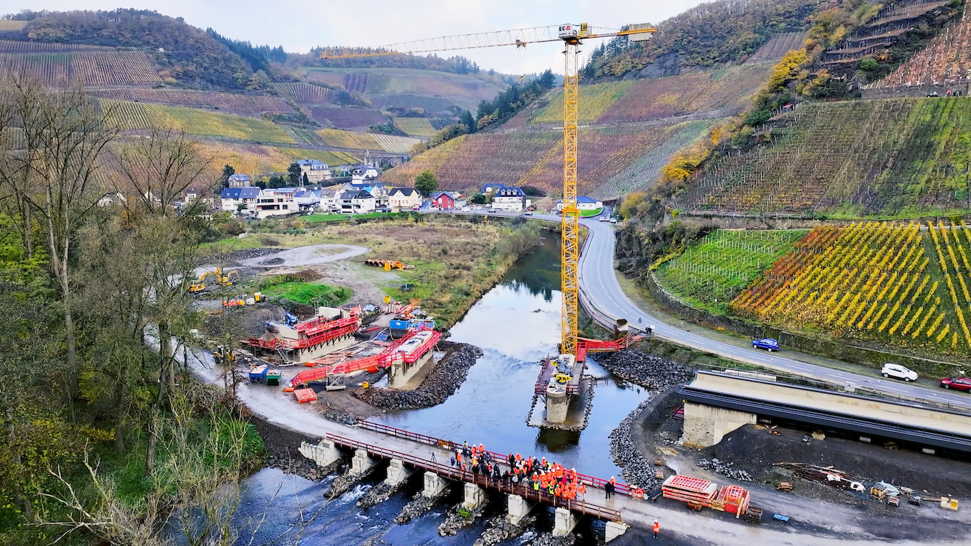 Ein Fluss mit Baugeräten und einer Brücke im Hintergrund, die an einem Bauprojekt arbeitet.