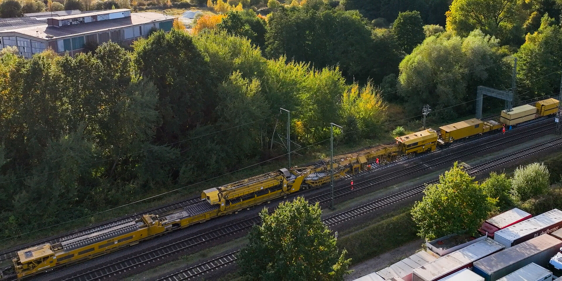 Luftaufnahme eines Zuges, der auf den Gleisen fährt, umgeben von grünen Landschaften und Bäumen.