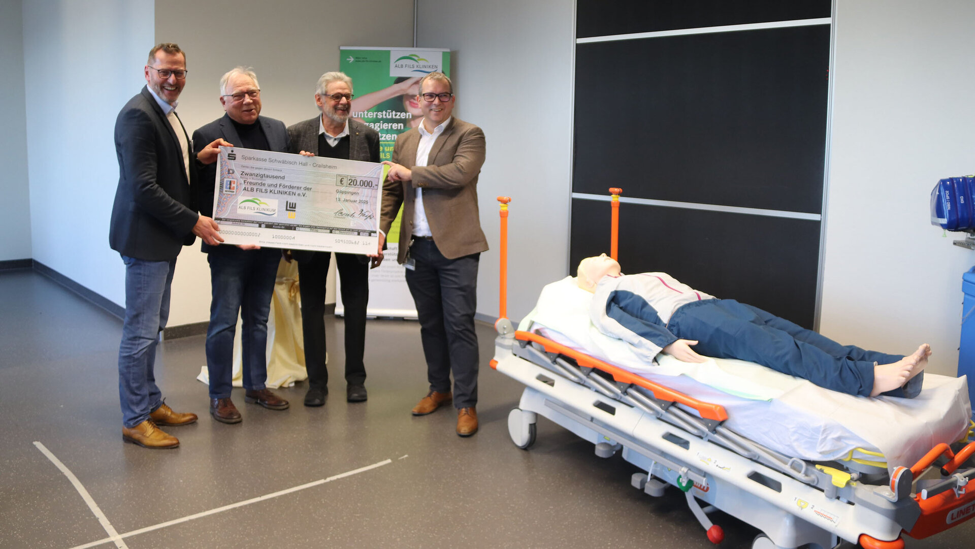 Vier Männer stehen zusammen und halten einen großen Scheck über 20.000 Euro für die Unterstützung von Kliniken.