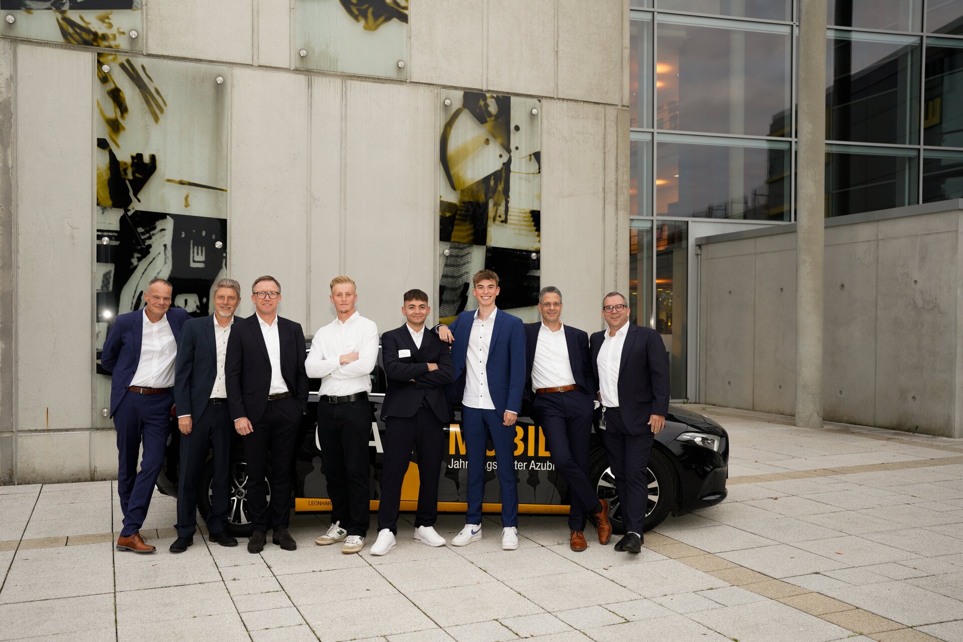Menschen stehen vor einem Mercedes in einer modernen Umgebung.