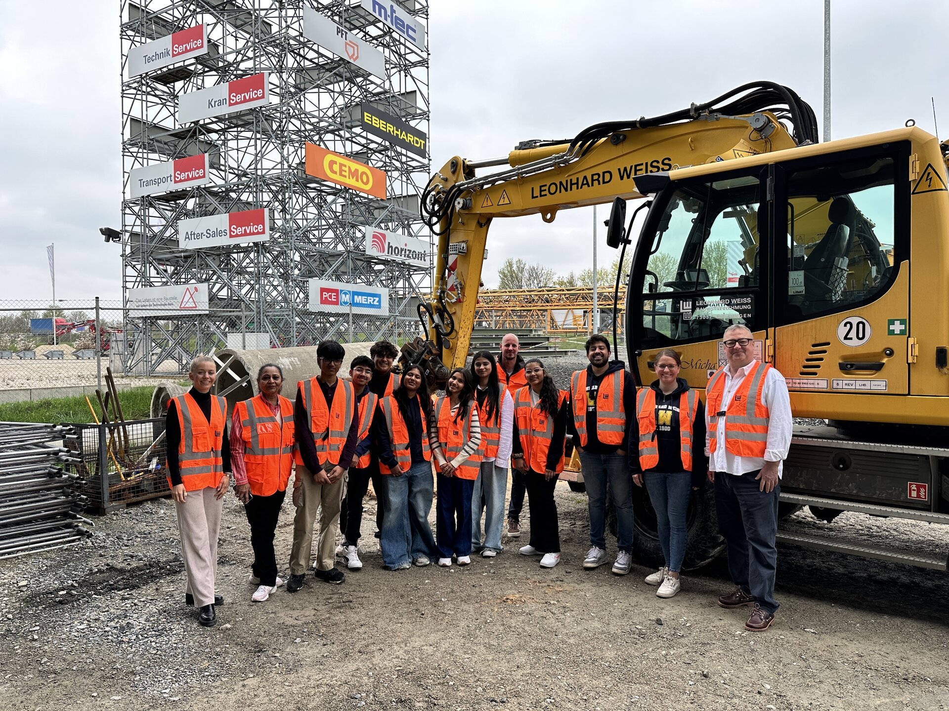 Eine Gruppe von Menschen steht vor einem Bagger.