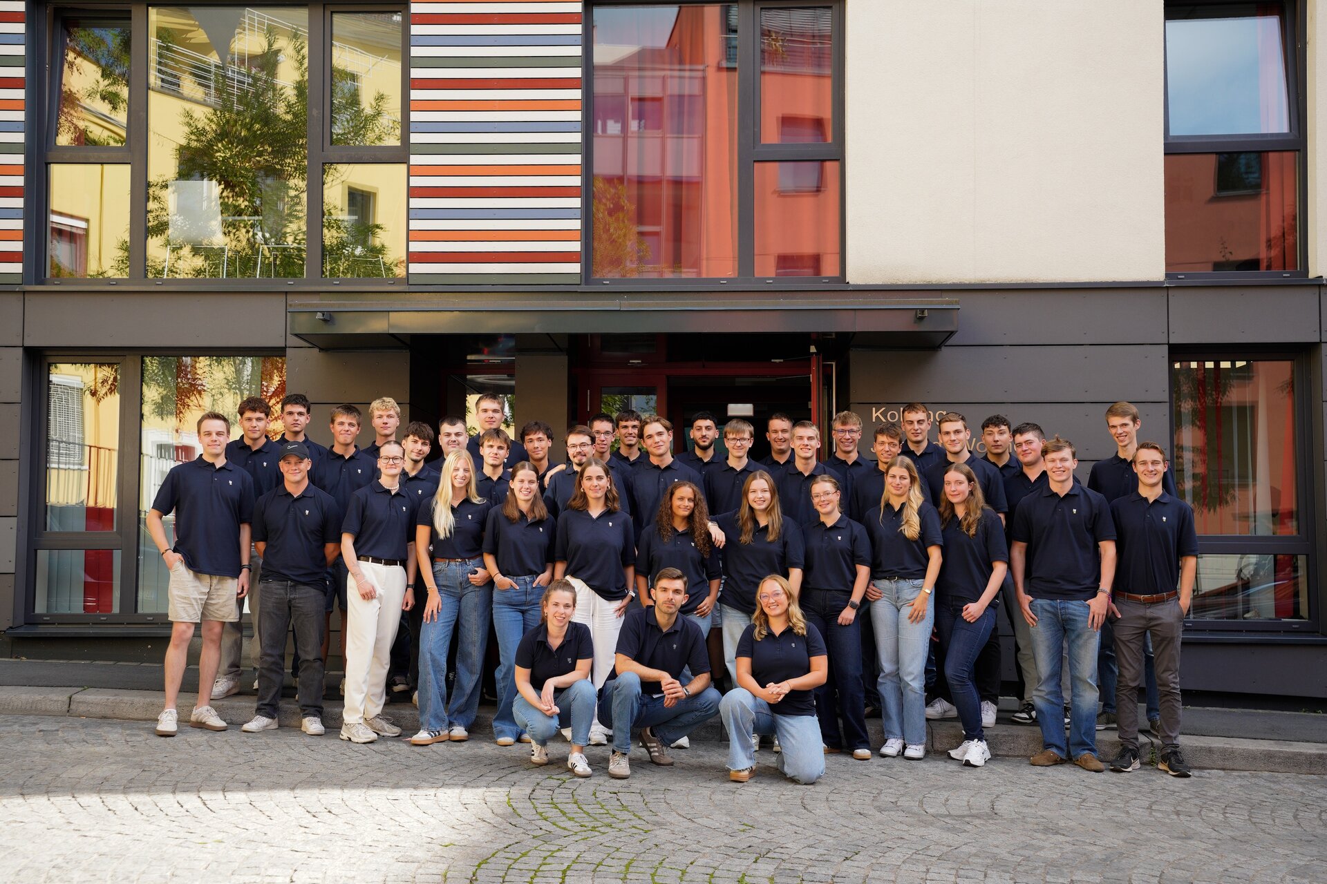 Eine Gruppe von Menschen steht vor einer Wand und posiert für ein Foto.