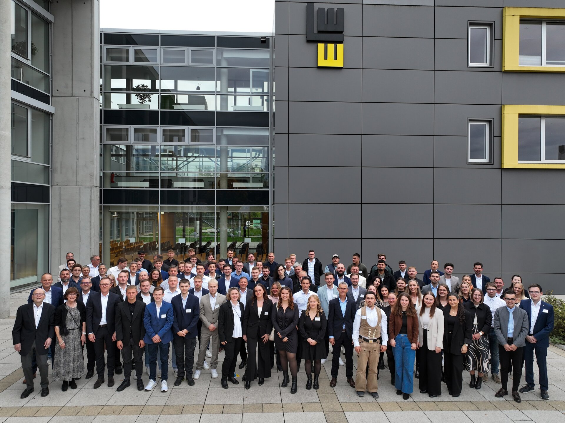 Eine Gruppe von Menschen steht vor einem Gebäude und posiert für ein Foto.