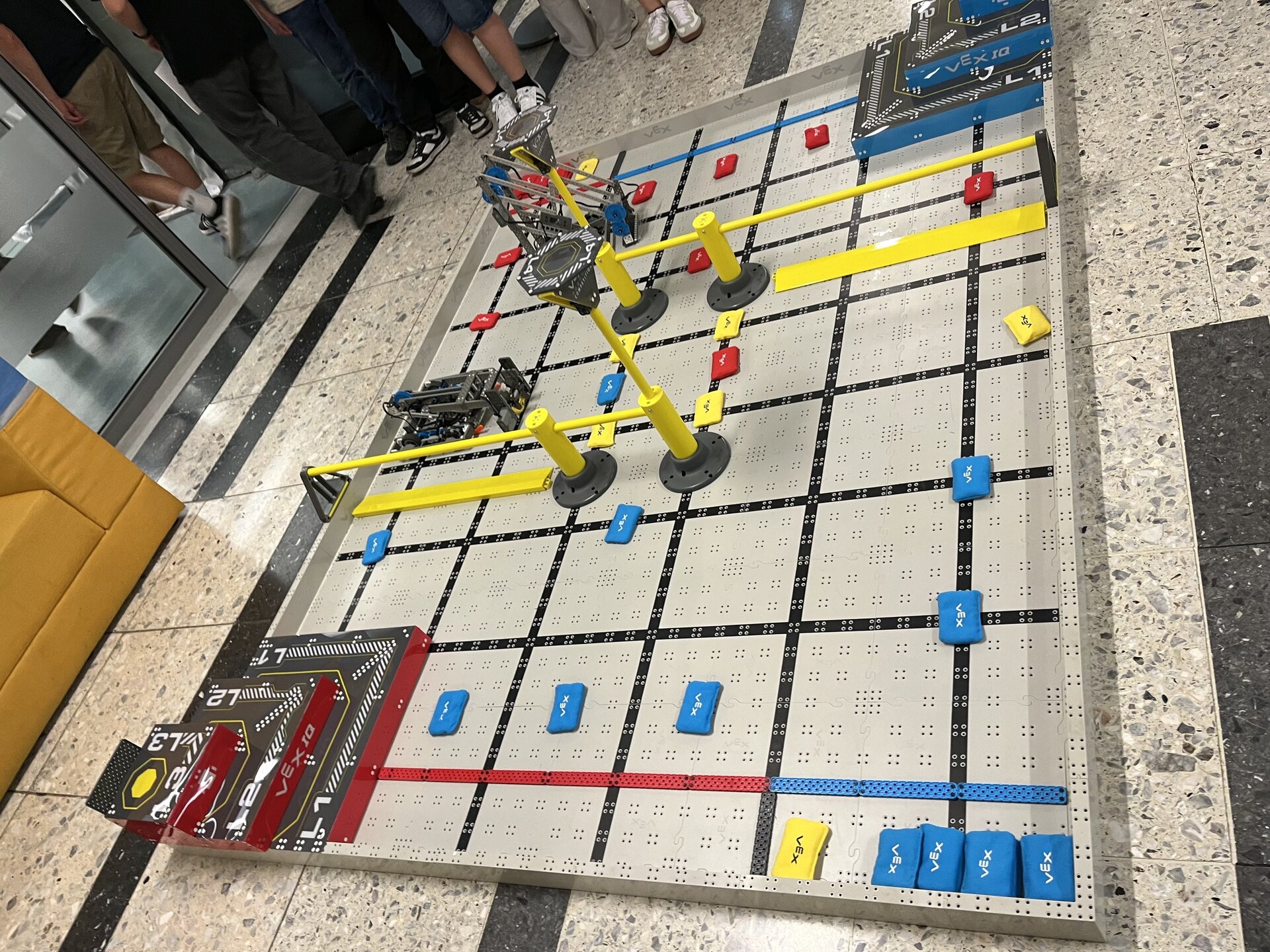 Eine große Lego-Baustelle auf dem Boden, umgeben von mehreren Personen, die interessiert zuschauen.